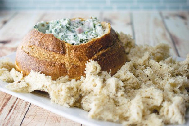 A round bread loaf is the beginning of this delicious spinach-ham dip.